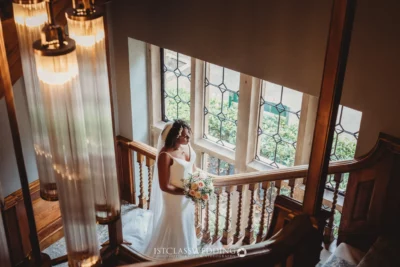 Bride holding bouquet on vintage staircase.