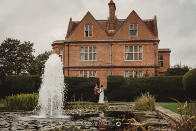 Couple by fountain at manor house wedding.