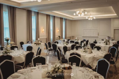 Elegant wedding reception room setup with tables and decor.