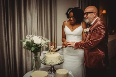 Couple cutting wedding cake together.