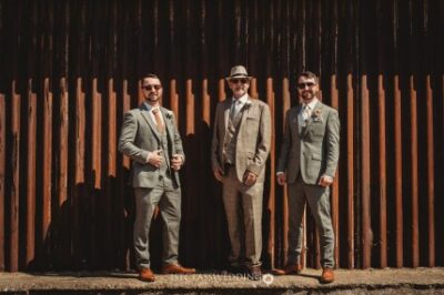 Three men in suits at a wedding event.