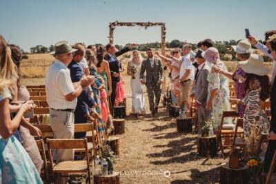 Outdoor wedding ceremony with guests and couple walking.