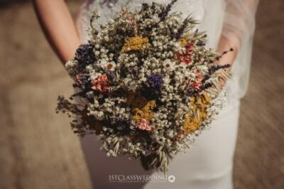 Bride holding colorful wildflower wedding bouquet.