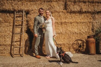 Couple with dog at rustic hay bale wedding.