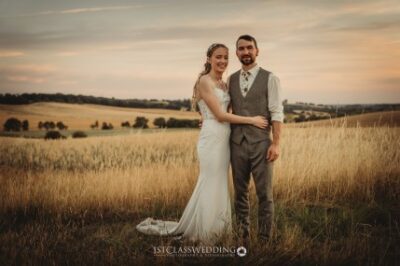 Couple posing in field at sunset on wedding day.