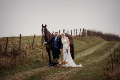 Couple with horse and dogs at countryside wedding.