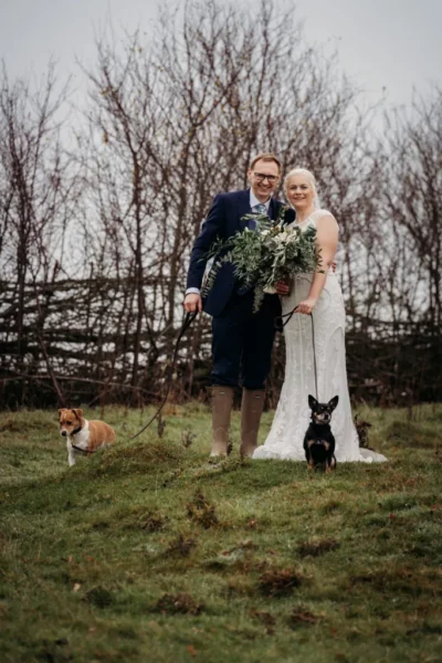 Couple with dogs at wedding outdoors.