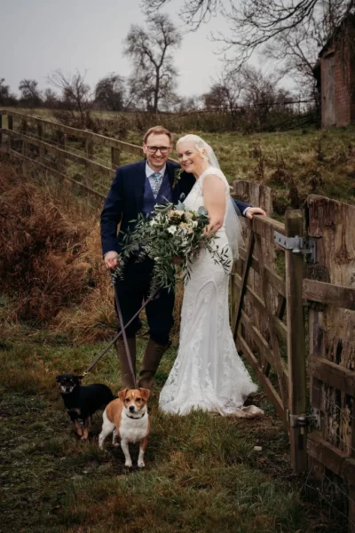 Couple with dogs at rustic wedding outdoors.