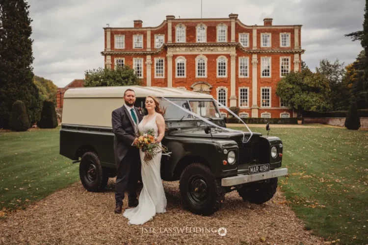 Wedding couple with classic Land Rover at estate.
