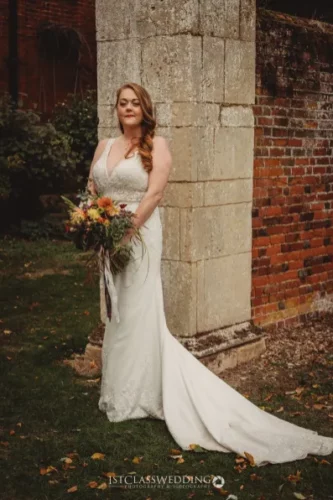 Bride with bouquet in elegant wedding dress outdoors.