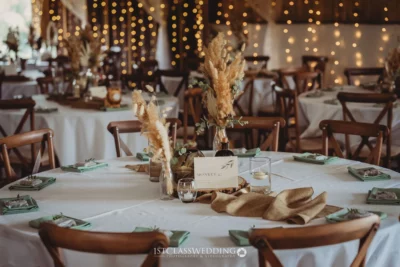 Rustic wedding table setting with fairy lights background.