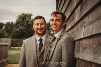 Two smiling grooms in suits at wedding.