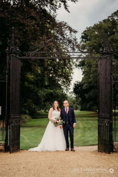 Couple posing at ornate gate after wedding ceremony.