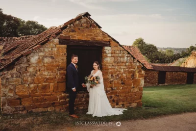 Bride and groom outside rustic stone barn.