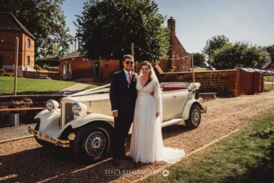 Bride and groom with vintage wedding car.