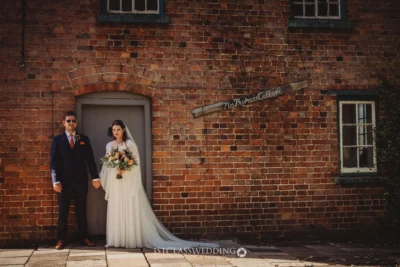 Bride and groom outside historic brick cottage.