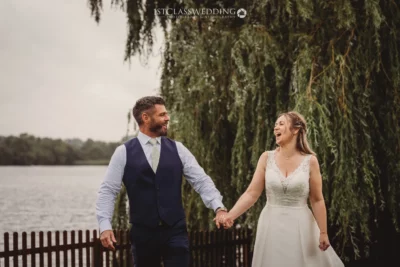 Joyful newlyweds holding hands by the lake.
