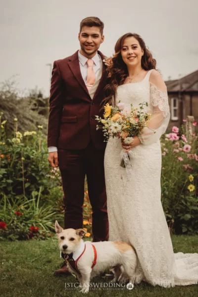 Wedding couple with dog in garden setting.