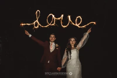 Wedding couple with sparkler writing 'love' at night.