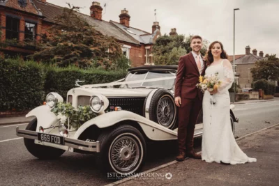 Wedding couple posing with vintage car.