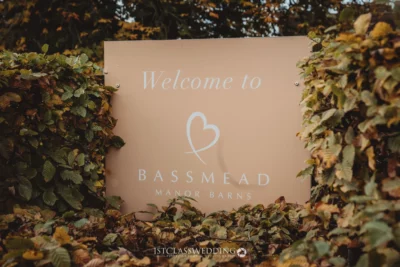 Welcome sign at Bassmead Manor Barns surrounded by foliage.