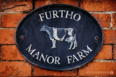 Vintage Furtho Manor Farm sign with cow on brick wall.