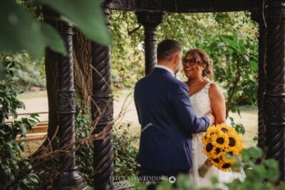 Bride and groom smiling with sunflower bouquet.