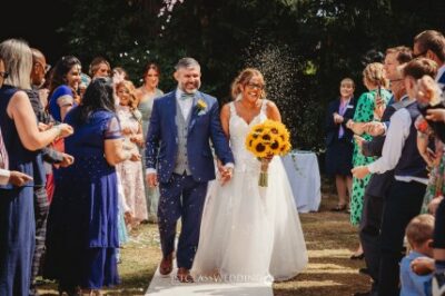 Newlyweds with guests tossing confetti at outdoor wedding