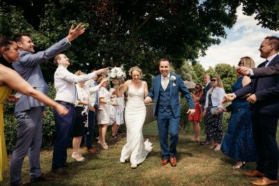 Bride and groom joyfully exiting ceremony with confetti.