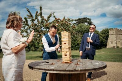 Guests playing giant Jenga at outdoor wedding reception.