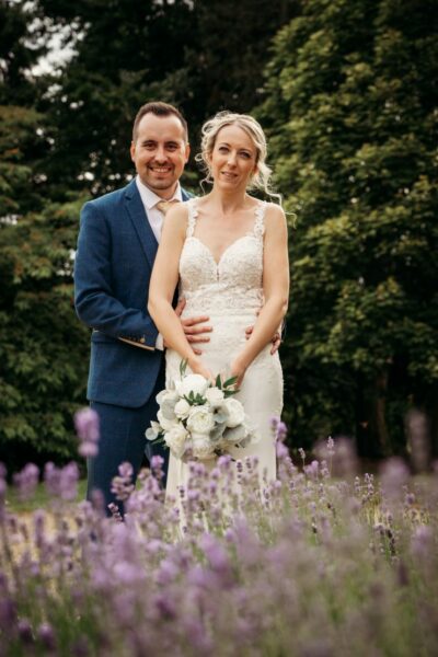 Couple in wedding attire posing in lavender field.