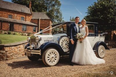 Couple with vintage car on wedding day.