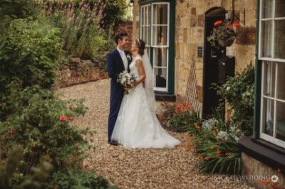 Bride and groom embracing in garden pathway.