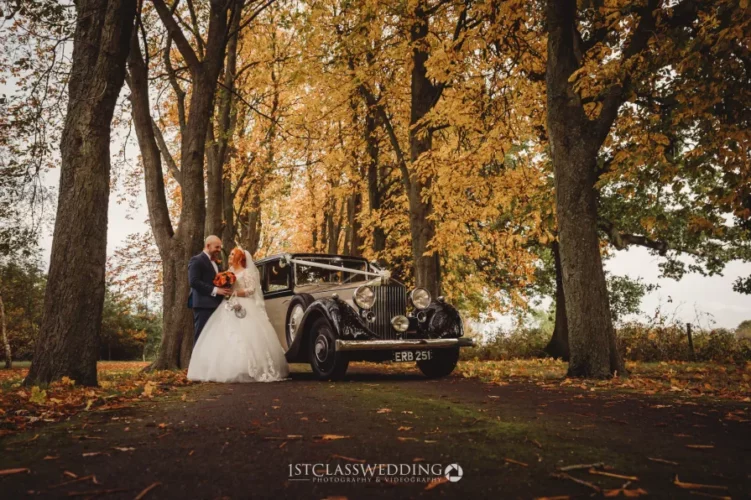Wedding couple with vintage car in autumn park.