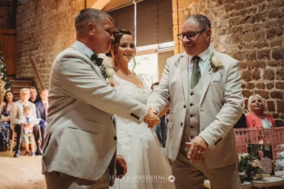 Wedding handshake between bride, groom, and father.