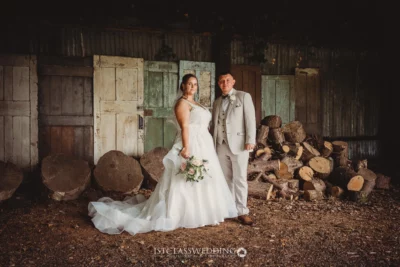 Bride and groom posing in rustic barn setting.