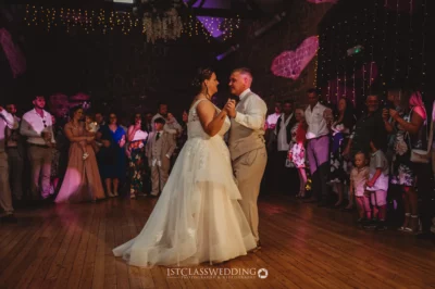 Wedding dance in a rustic venue with fairy lights.