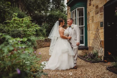 Bride and groom embracing in garden setting.