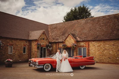 Bride and groom with vintage car at wedding venue.