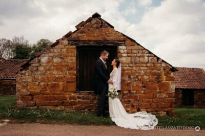 Couple wedding photo outside rustic stone building.