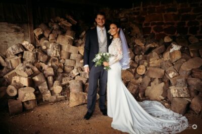 Couple at rustic wedding with log backdrop.