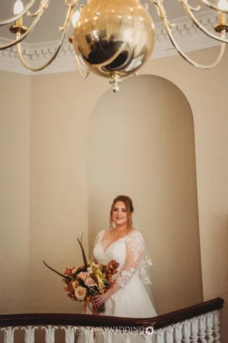 Bride with bouquet under chandelier in elegant setting.