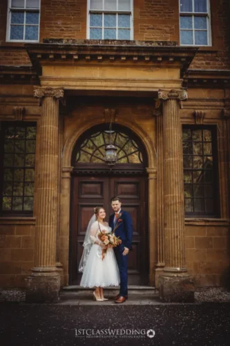 Couple posing at historic building entrance on wedding day