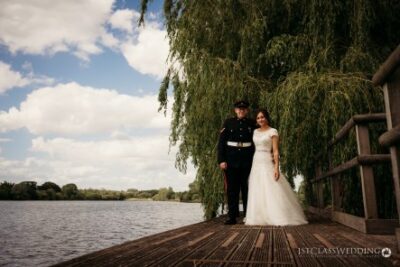 Bride and groom by lake with weeping willow trees.
