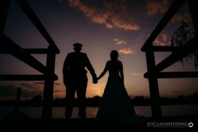 Silhouetted couple holding hands at sunset.