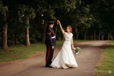 Military groom and bride dancing in park.