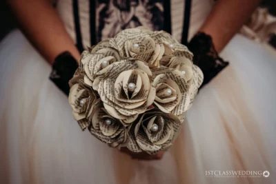 Bride holding paper flower bouquet with pearls.