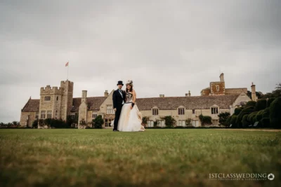 Wedding couple in front of historic British mansion.