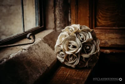 Vintage paper flower bouquet on rustic windowsill.