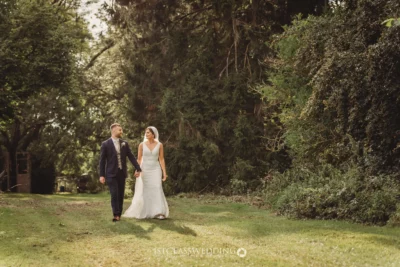 Couple walking in park on sunny wedding day